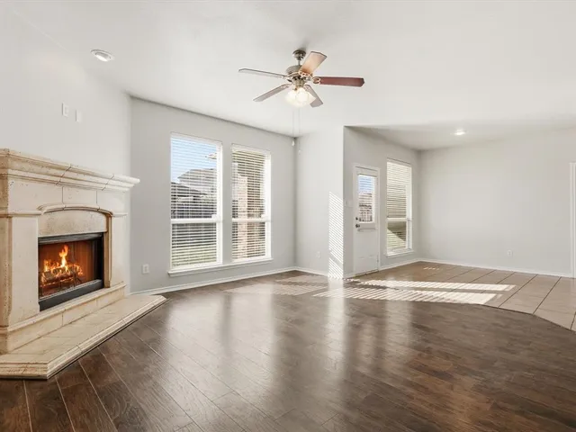 a view of an empty room with wooden floor fireplace and a window