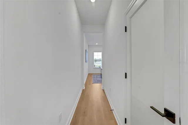 a view of a hallway with wooden floor and a bathroom