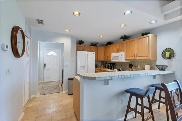 a kitchen with stainless steel appliances granite countertop a table chairs sink and cabinets