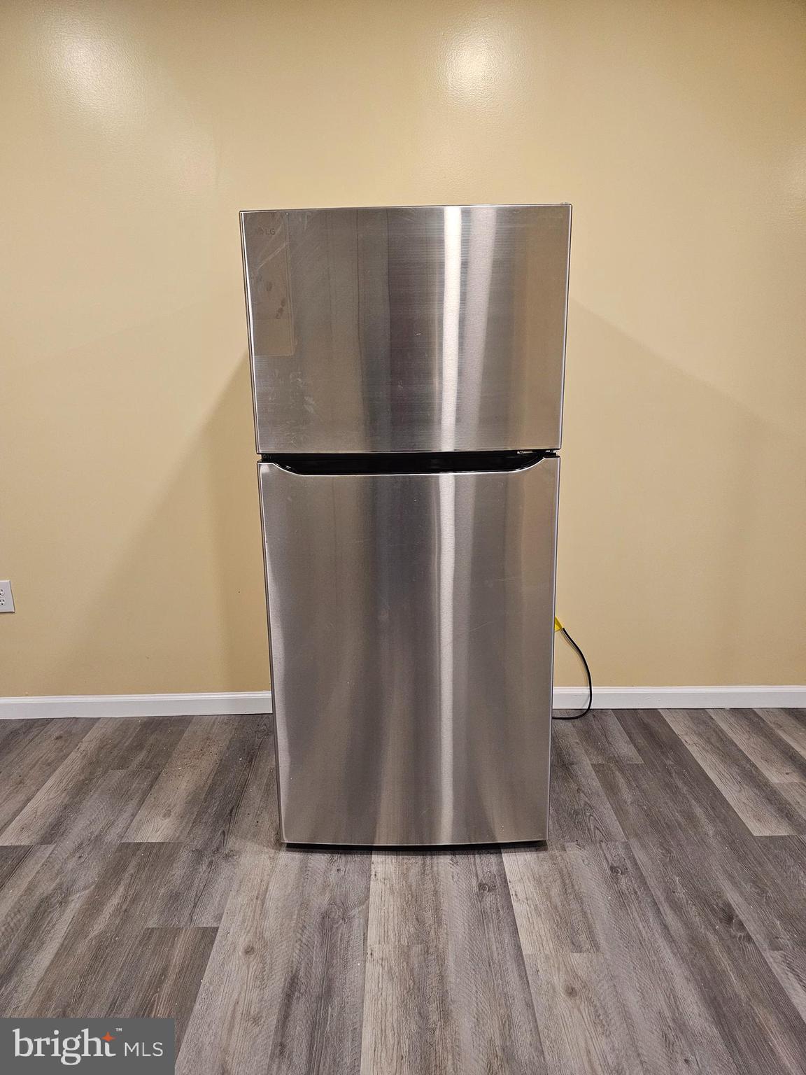 1535 North 60th Street, Unit A Philadelphia, PA 19151 - Photo 4 of 11 a view of a refrigerator in kitchen and an empty room with wooden floor