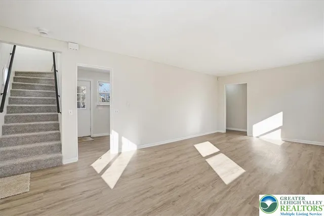 a view of an empty room with wooden floor and stairs