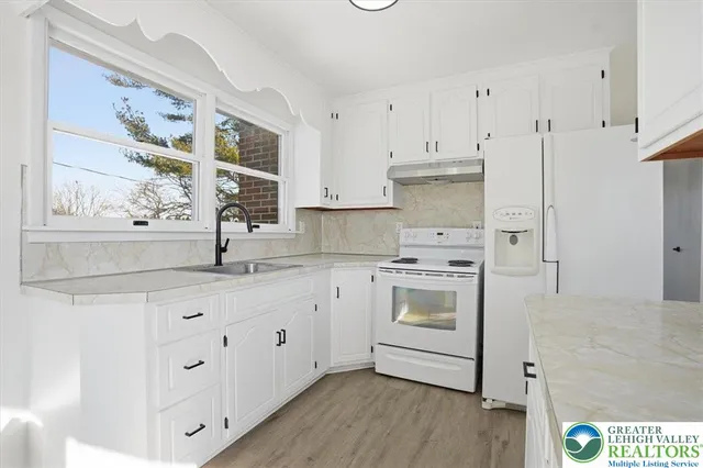 a kitchen with granite countertop white cabinets and white appliances