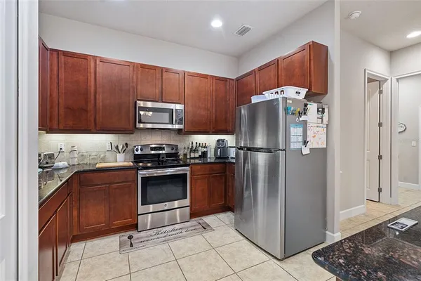 a kitchen with stainless steel appliances granite countertop a refrigerator and a stove top oven