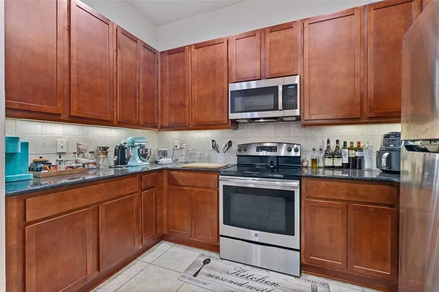 a kitchen with stainless steel appliances granite countertop wooden cabinets a stove top oven a sink and dishwasher