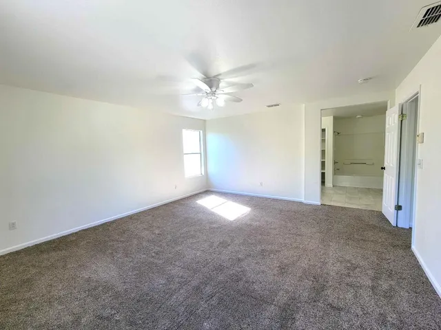 an empty room with windows and ceiling fan