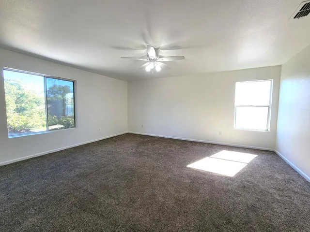 an empty room with windows and ceiling fan