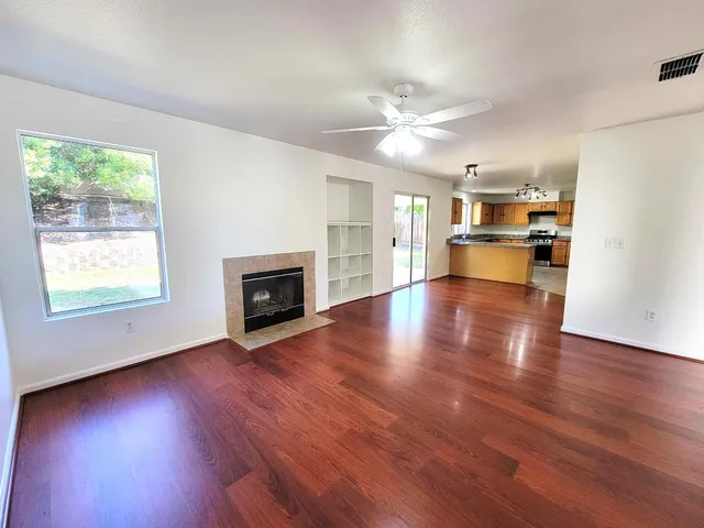 an empty room with wooden floor fireplace and windows