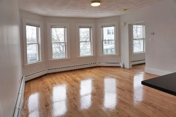 an empty room with wooden floor and windows