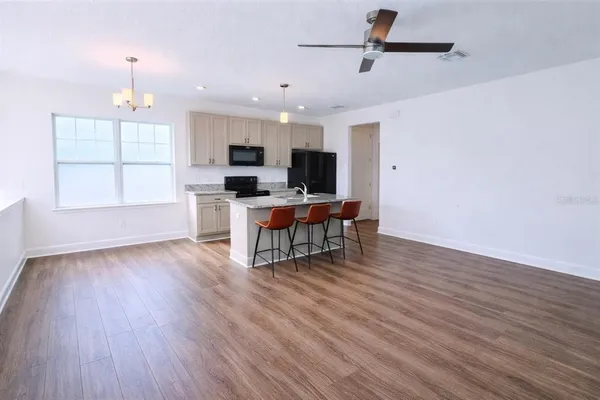 a kitchen with stainless steel appliances granite countertop a refrigerator a sink a stove a microwave and wooden floors