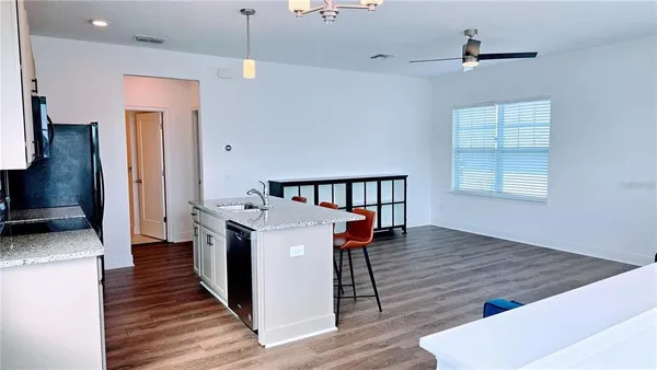 a kitchen with stainless steel appliances a dining table chairs stove refrigerator and cabinets