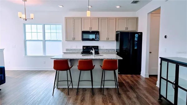 a living room with stainless steel appliances kitchen island granite countertop furniture a refrigerator a sink a stove and a microwave