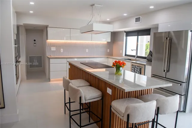 a kitchen with stainless steel appliances granite countertop a table chairs and a refrigerator