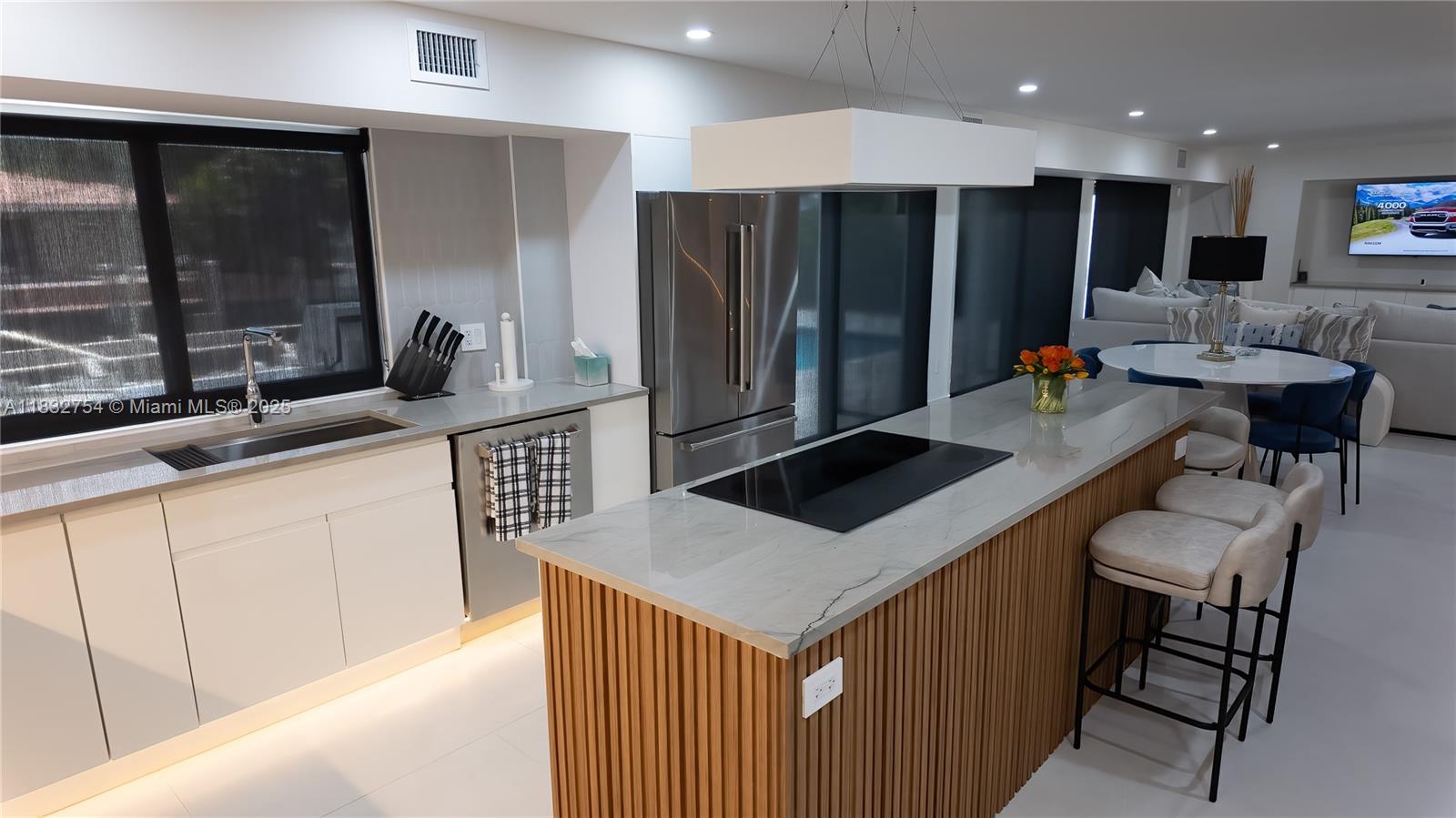 1240 Northeast 27th Terrace Pompano Beach, FL 33062 - Photo 36 of 98 a kitchen with kitchen island a counter top space a sink a refrigerator and chairs