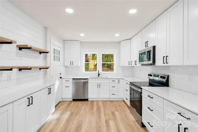 a large kitchen with stainless steel appliances granite countertop a sink and dishwasher a stove with wooden floors