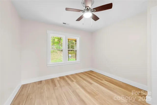 an empty room with a window and a fan