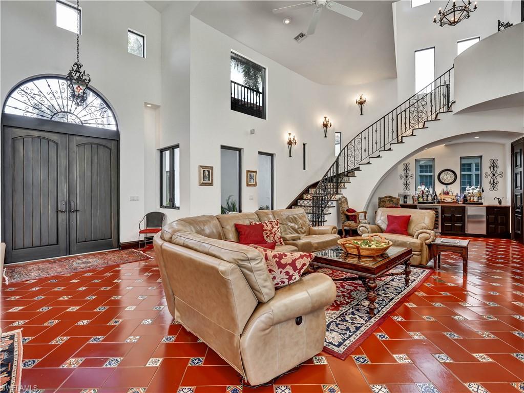 2535 Tarpon Road Naples, FL 34102 - Photo 5 of 50 Grand entry featuring a custom wrought iron spiral staircase with patterned tile risers, terracotta tile flooring with accent tiles, and a double-height ceiling