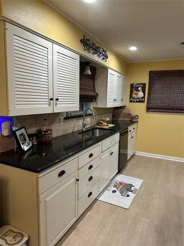 a kitchen with granite countertop a sink a stove and cabinets