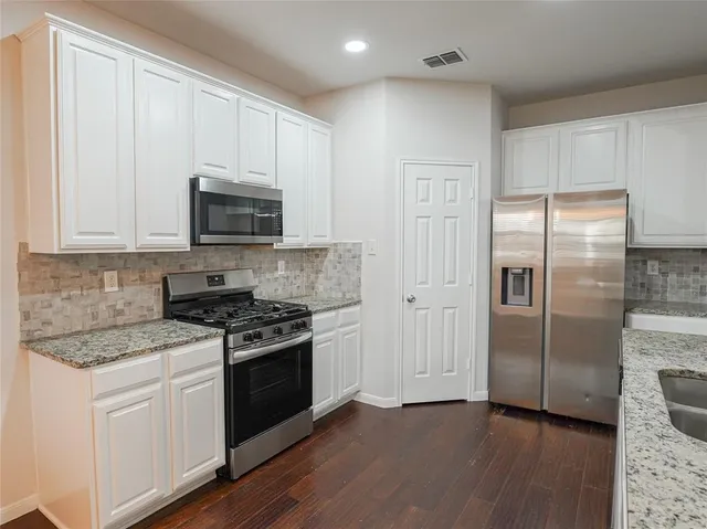 a kitchen with cabinets stainless steel appliances and wooden floor