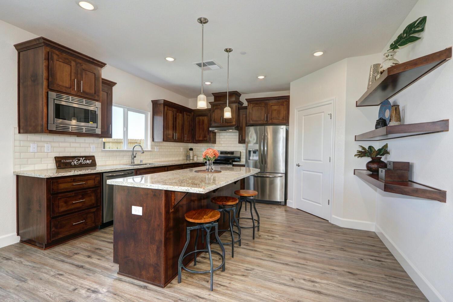 932 Norman Road Galt, CA 95632 - Photo 11 of 21 a kitchen with stainless steel appliances granite countertop a refrigerator a stove top oven a sink dishwasher and white cabinets with wooden floor