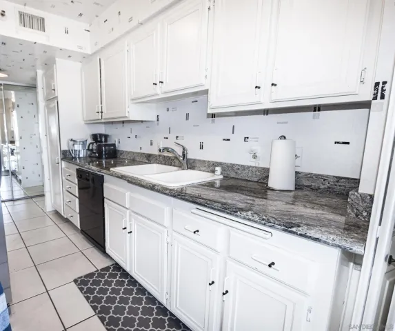 a kitchen with granite countertop white cabinets and white appliances
