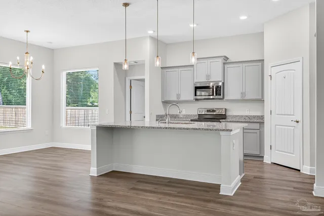 a kitchen with stainless steel appliances granite countertop a stove a sink and a refrigerator with wooden floors