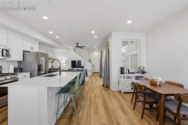 a kitchen with stainless steel appliances granite countertop a stove top oven a sink dishwasher a refrigerator and a dining table with wooden floor