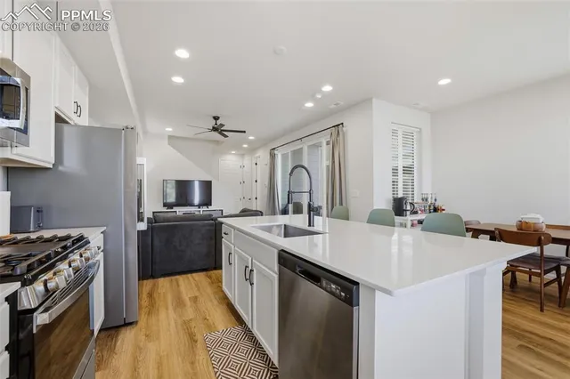 a kitchen with stainless steel appliances a dining table chairs refrigerator and microwave