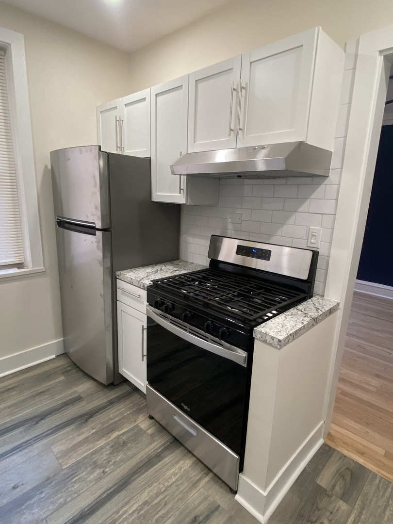 2210 East 70th Street, Unit 1 Chicago, IL 60649 - Photo 15 of 15 a kitchen with granite countertop a stove and a refrigerator