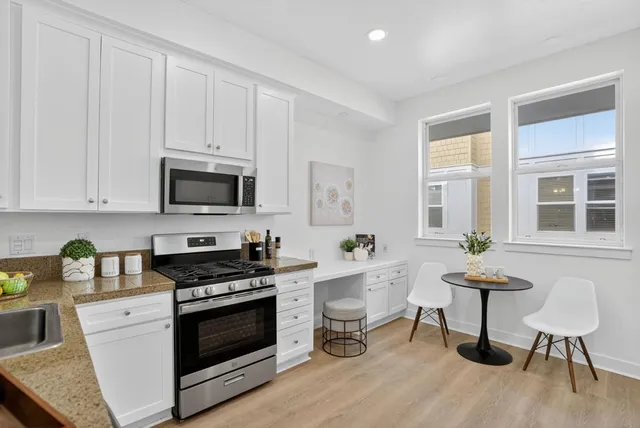 a kitchen with stainless steel appliances a stove a sink cabinets and wooden floor