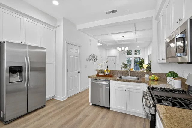 a kitchen with stainless steel appliances a sink a stove a refrigerator and cabinets
