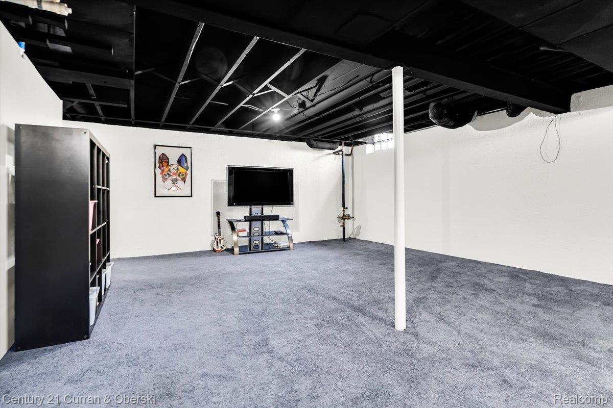 21439 Hall Road Trenton, MI 48183 - Photo 23 of 35 Spacious room featuring light blue carpeting, white painted walls, and a black painted exposed ceiling