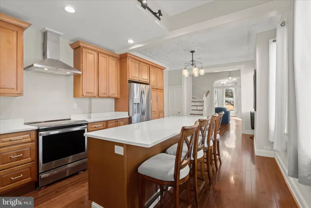 a kitchen with stainless steel appliances granite countertop a stove a refrigerator a sink a dining table and chairs with wooden floor