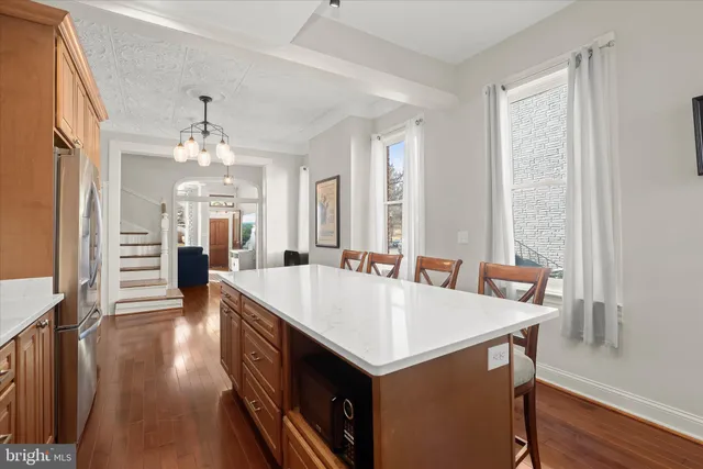 a large white kitchen with a window and refrigerator