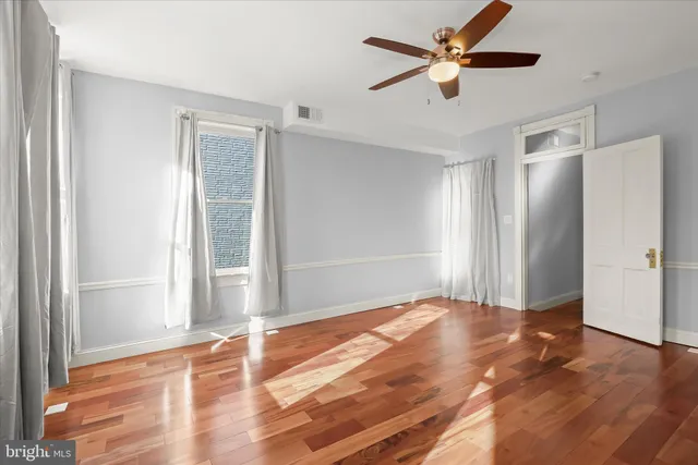 a view of an empty room with window and wooden floor