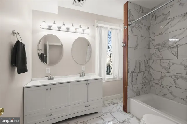 a bathroom with a double vanity sink mirror and bathtub