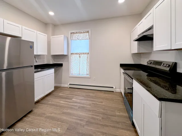 a kitchen with granite countertop a refrigerator a sink a stove a microwave and wooden cabinets