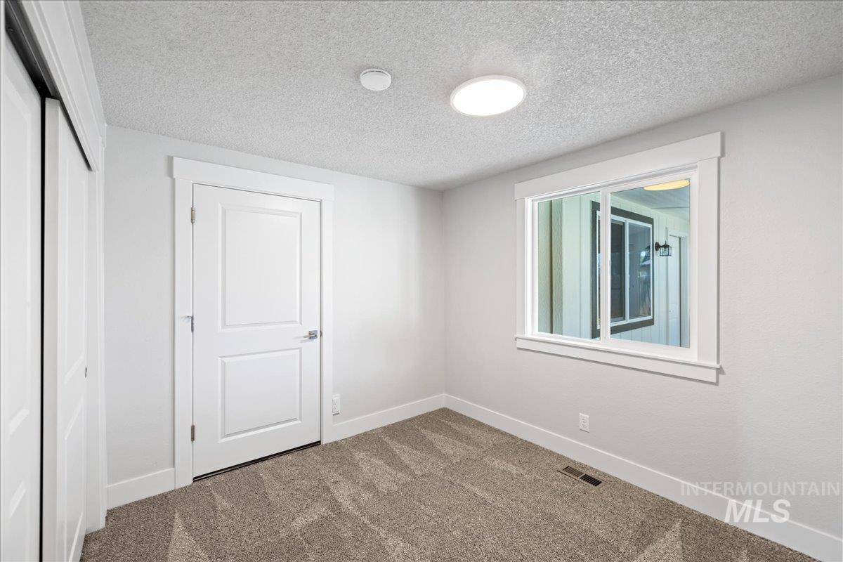 1309 West Maple Avenue Meridian, ID 83642 - Photo 17 of 50 Unfurnished bedroom featuring carpet, a textured ceiling, and a closet