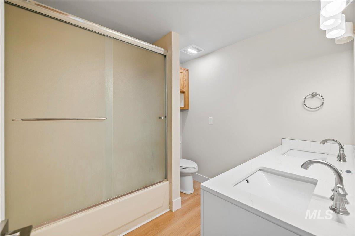 1309 West Maple Avenue Meridian, ID 83642 - Photo 24 of 50 Bathroom featuring double vanity, light wood-type flooring, and shower / bath combination with glass door