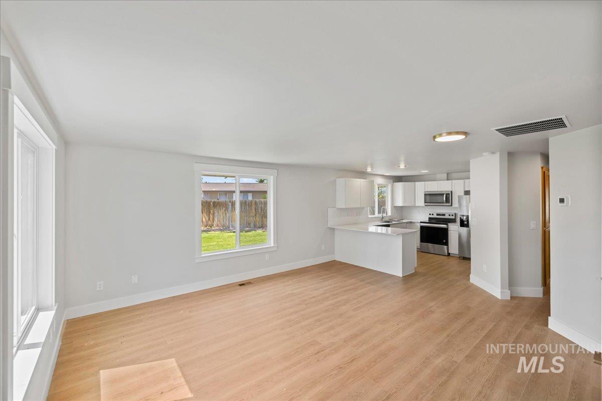 1309 West Maple Avenue Meridian, ID 83642 - Photo 50 of 50 Kitchen featuring white cabinetry, appliances with stainless steel finishes, open floor plan, light wood-type flooring, and a peninsula