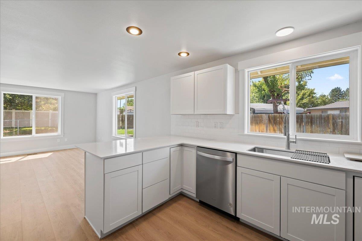 1309 West Maple Avenue Meridian, ID 83642 - Photo 33 of 50 Kitchen featuring decorative backsplash, plenty of natural light, dishwasher, light wood-style floors, and recessed lighting