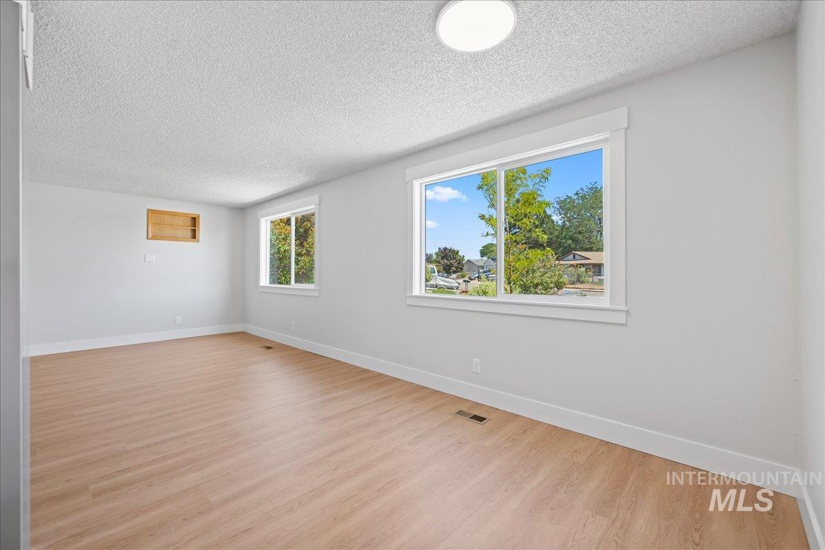 1309 West Maple Avenue Meridian, ID 83642 - Photo 8 of 50 Unfurnished room featuring a textured ceiling and light wood-type flooring