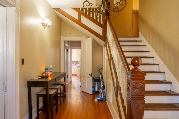 a view of a hallway with wooden floor and staircase