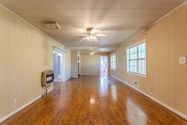 a view of an empty room with window and wooden floor