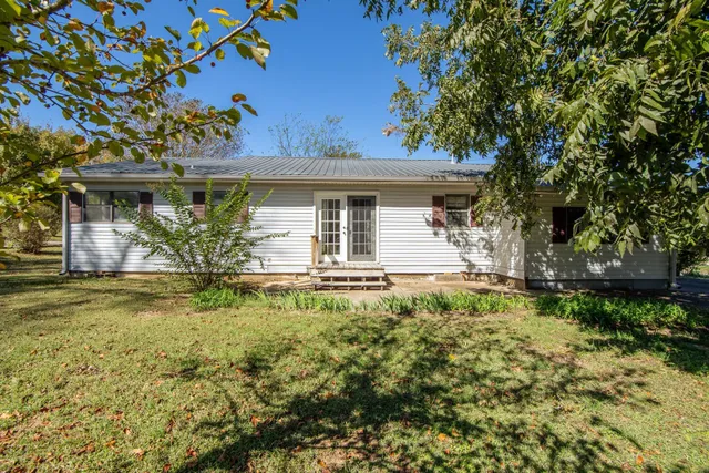 a house is sitting in middle of the green field