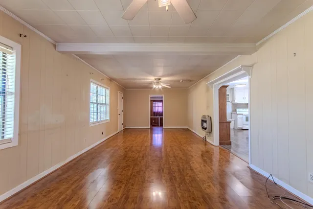 a view of an empty room with wooden floor and a window