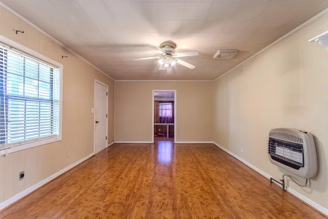 a view of an empty room with window and wooden floor
