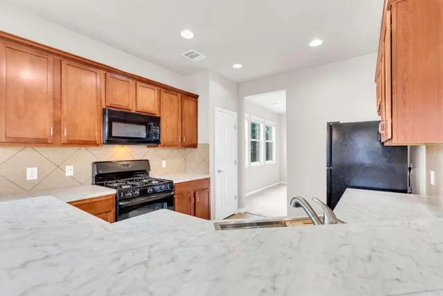 a view of kitchen with stainless steel appliances granite countertop stove top oven and cabinets