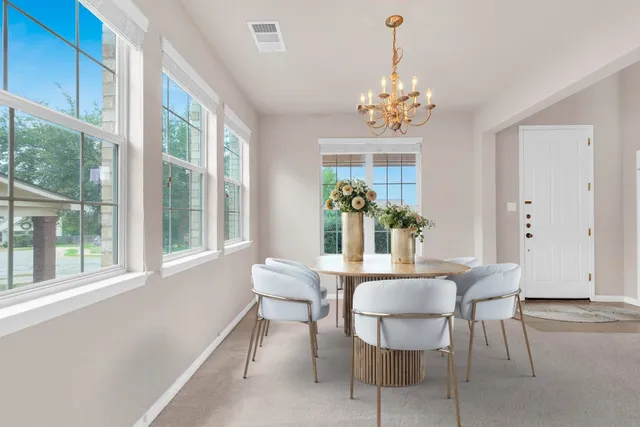 a view of a dining room with furniture a chandelier and a window