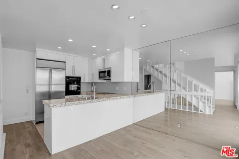 a large white kitchen with a refrigerator a counter top space and cabinets