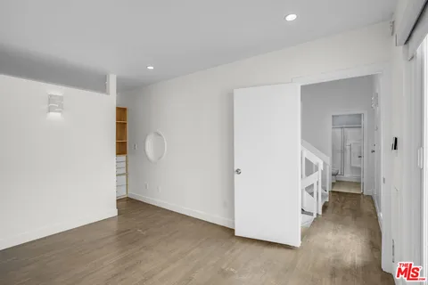 a view of an empty room with wooden floor and a bathroom